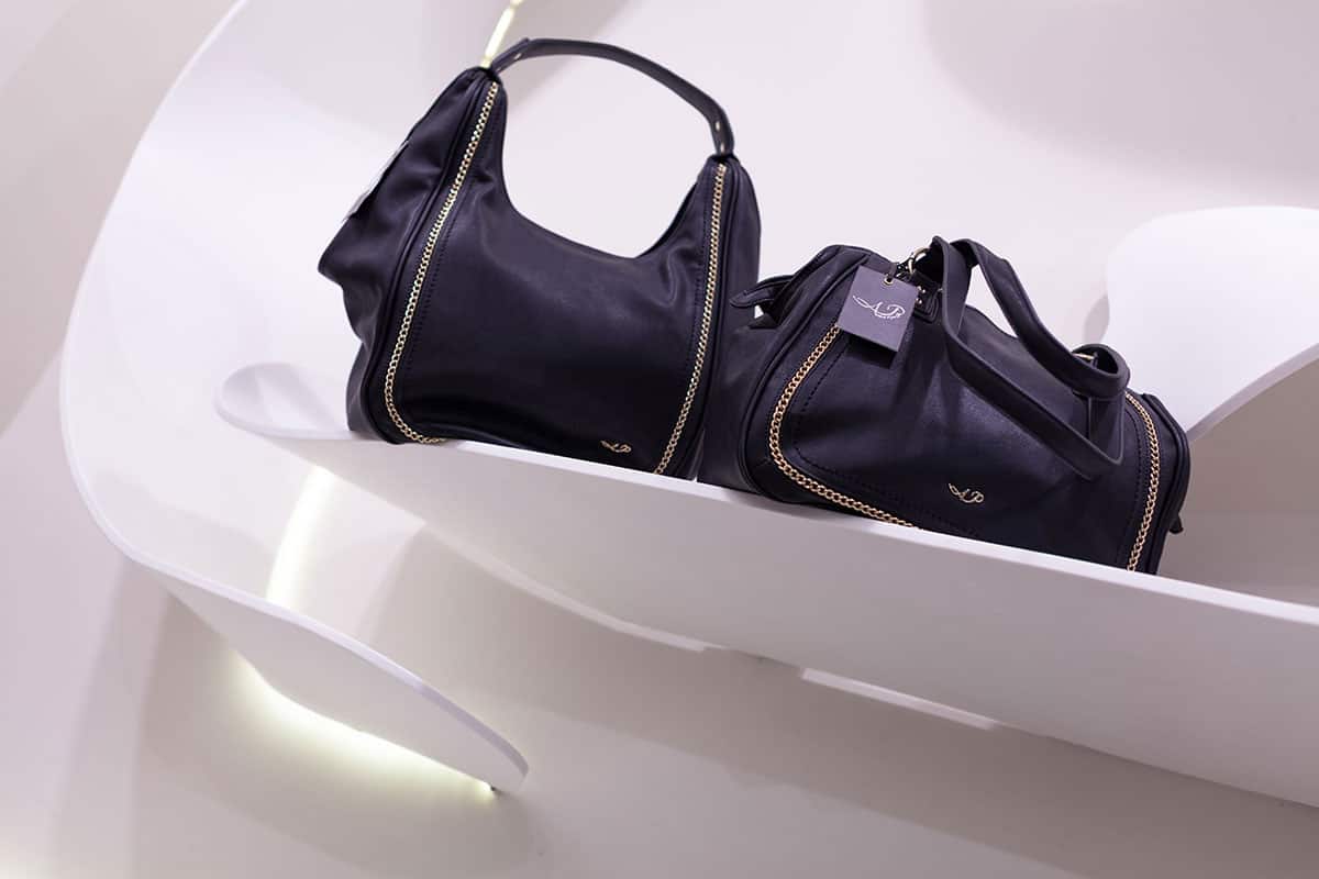 תצוגת תיקים ואביזרים בחנות NOME, על גבי מדפי קוריאן מעוצבים המשתלבים עם תאורה סמויה ליצירת אווירה יוקרתית.